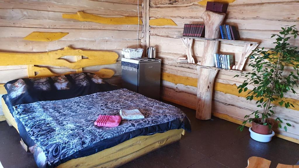 1 dormitorio con 1 cama en una pared de madera en Viesu māja Kaķis krūzē, en Folvarcīši