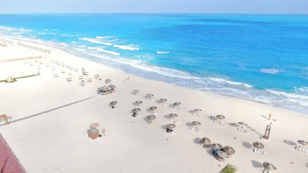 een luchtzicht op een strand met parasols en de oceaan bij Tolip North Coast Hotel in El Alamein