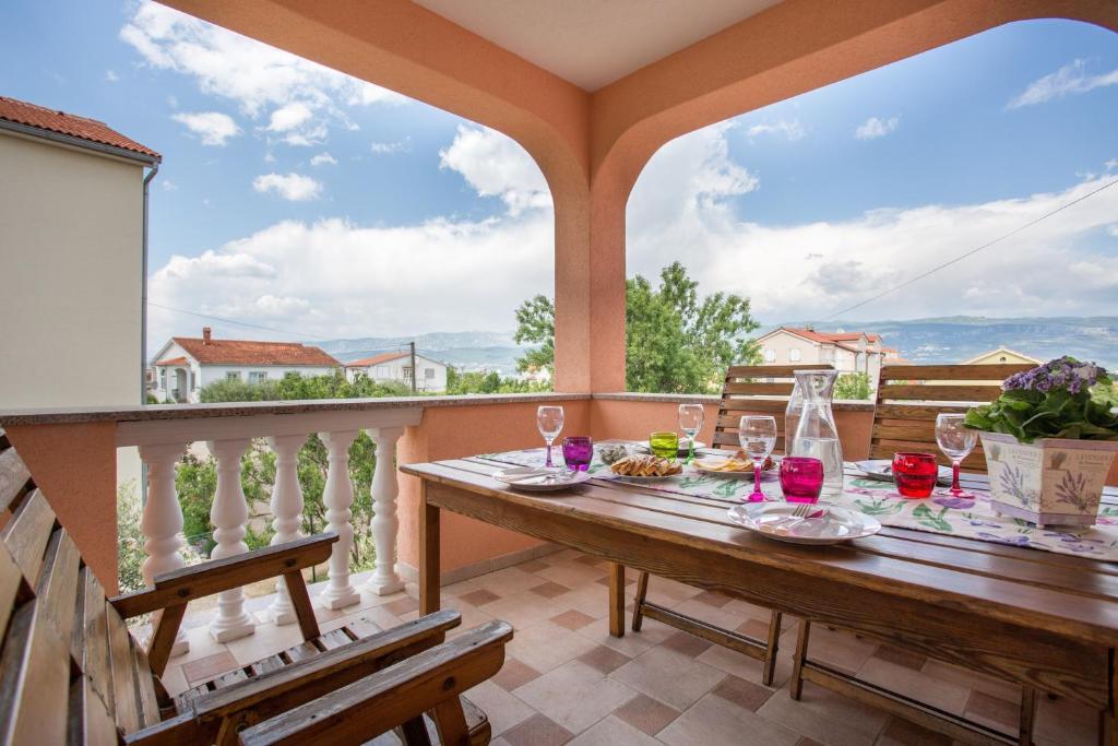 a wooden table on a balcony with a table and chairs at Apartman Lana in Šilo