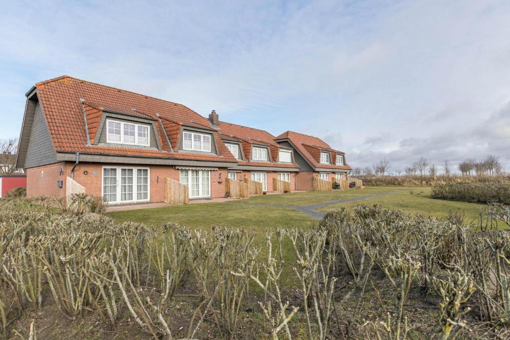 a large brick house on a grass field at Ferienwohnung Nordseeperle in Friedrichskoog-Spitze