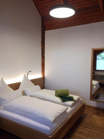 Schlafzimmer mit einem Bett mit weißer Bettwäsche und einem Spiegel in der Unterkunft Naturata Hotel in Überlingen
