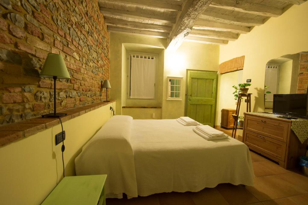 um quarto com uma cama branca e uma parede de tijolos em Agriturismo Arte Contadina em Fiorenzuola dʼArda