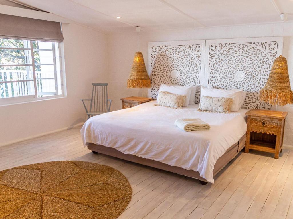 a bedroom with a large white bed and a window at River House in Plettenberg Bay