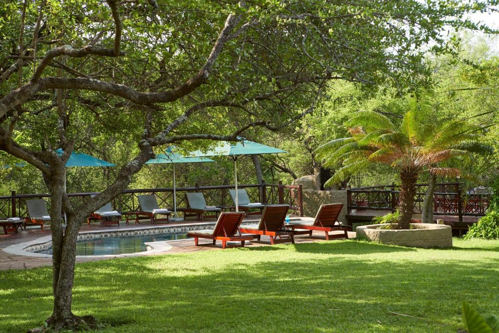 a yard with chairs and umbrellas next to a pool at Grand Kruger Lodge and Spa in Marloth Park