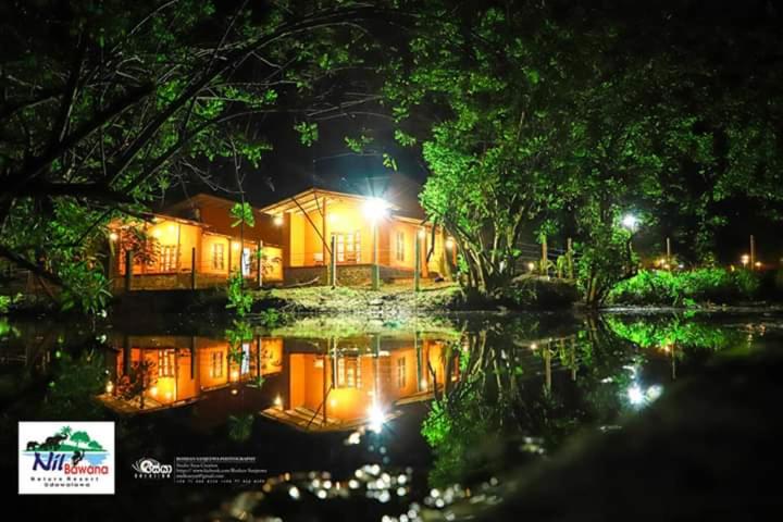 een huis 's nachts met een reflectie in het water bij Nil Bawana Nature Resort in Udawalawe