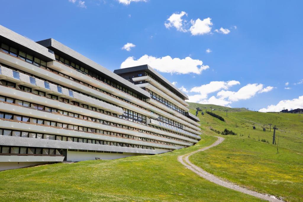 a building with a grassy hill next to it at SOWELL RESIDENCES Crêt Voland in Les Menuires
