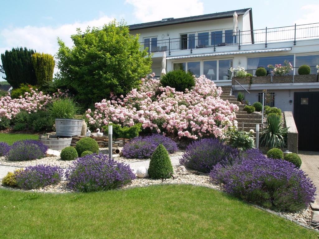 um jardim em frente a uma casa com flores cor-de-rosa em Weingut Bastian em Brauneberg