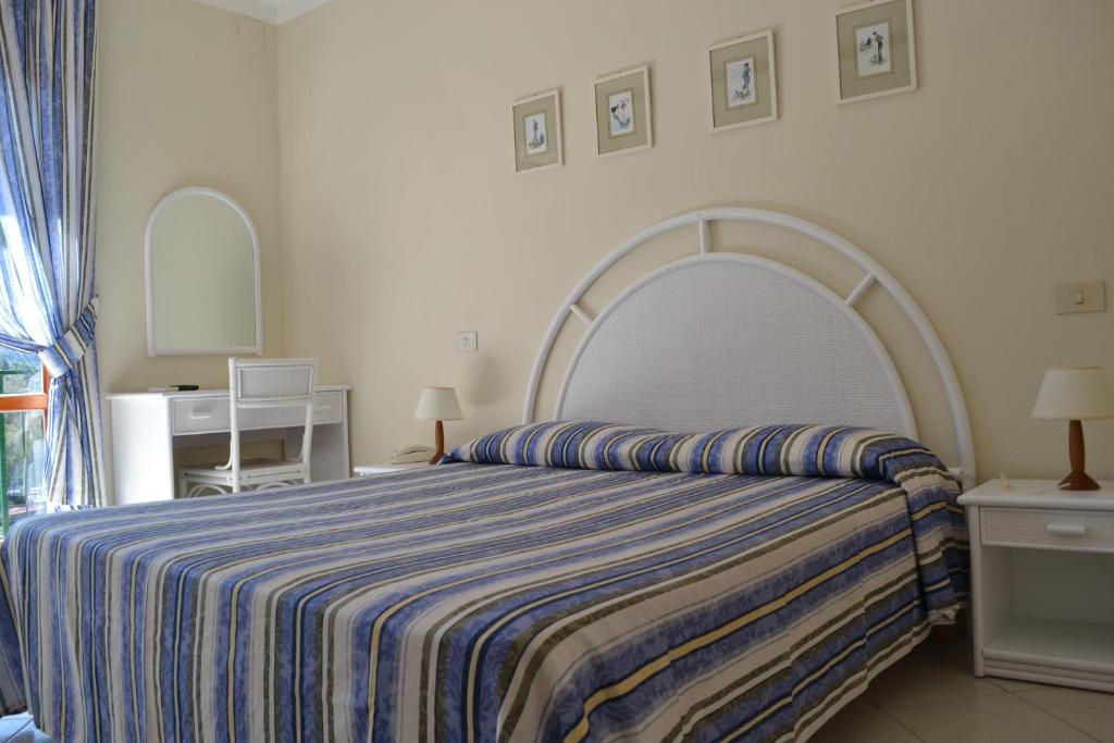 a bedroom with a large bed with a striped blanket at Hotel Danila in Portoferraio