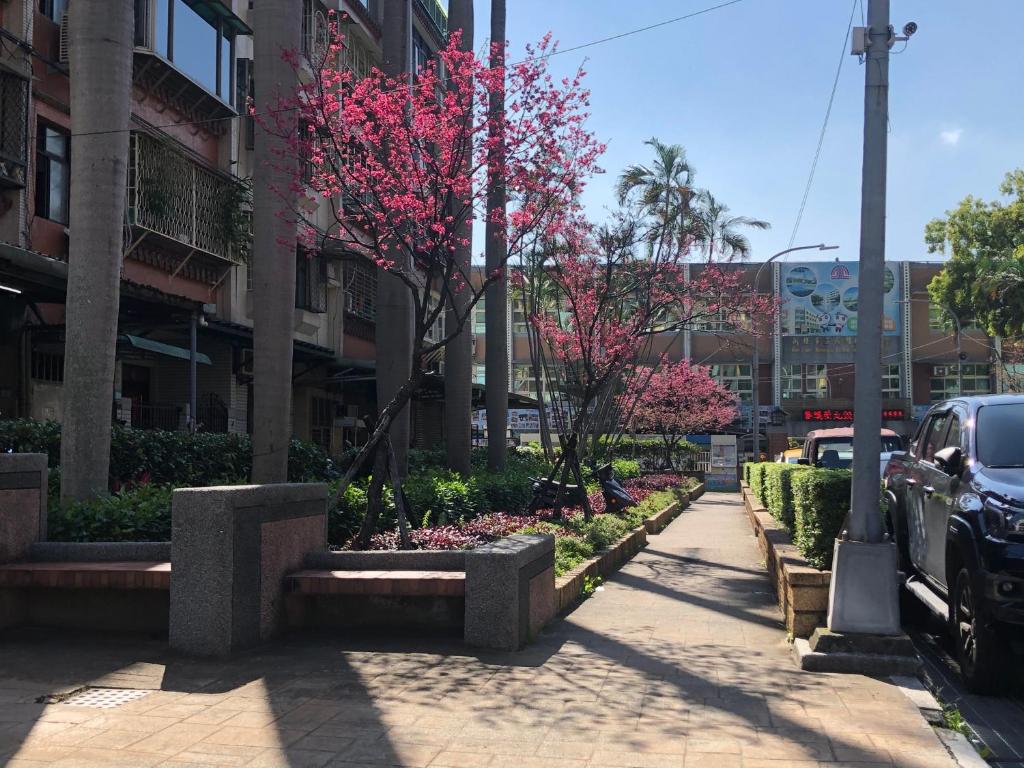 una strada con alberi con fiori rosa in una città di 紅色鐵門 a Taipei