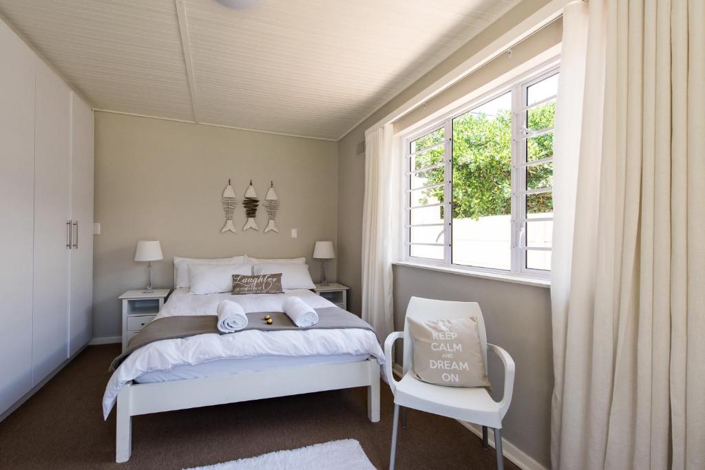 a bedroom with a white bed and a window at Melkbos Holiday Accommodation in Melkbosstrand