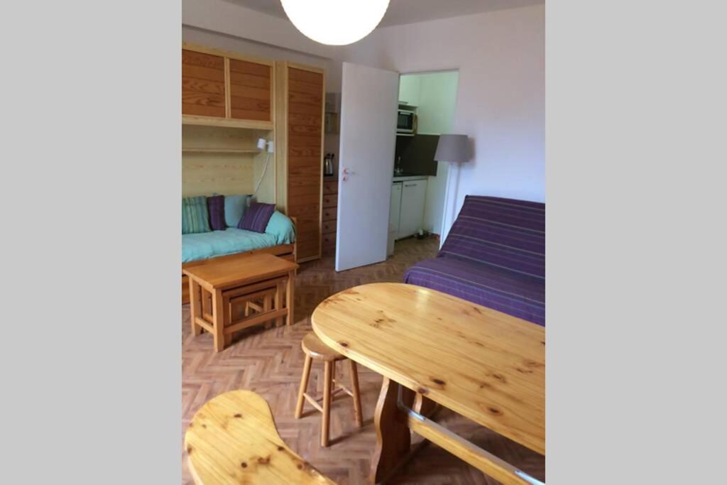 una sala de estar con una mesa y un sofá en Studio lumineux avec balcon 2/4 pers. plein centre, en La Bourboule