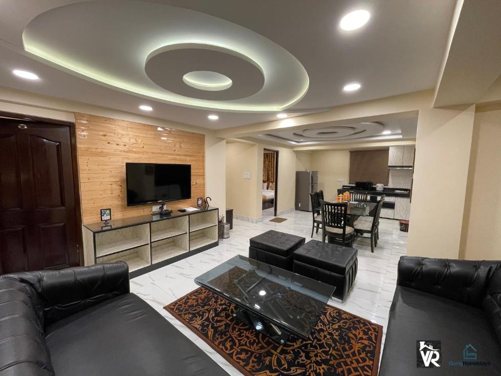 a living room with black furniture and a flat screen tv at Valley View Residency in Darjeeling