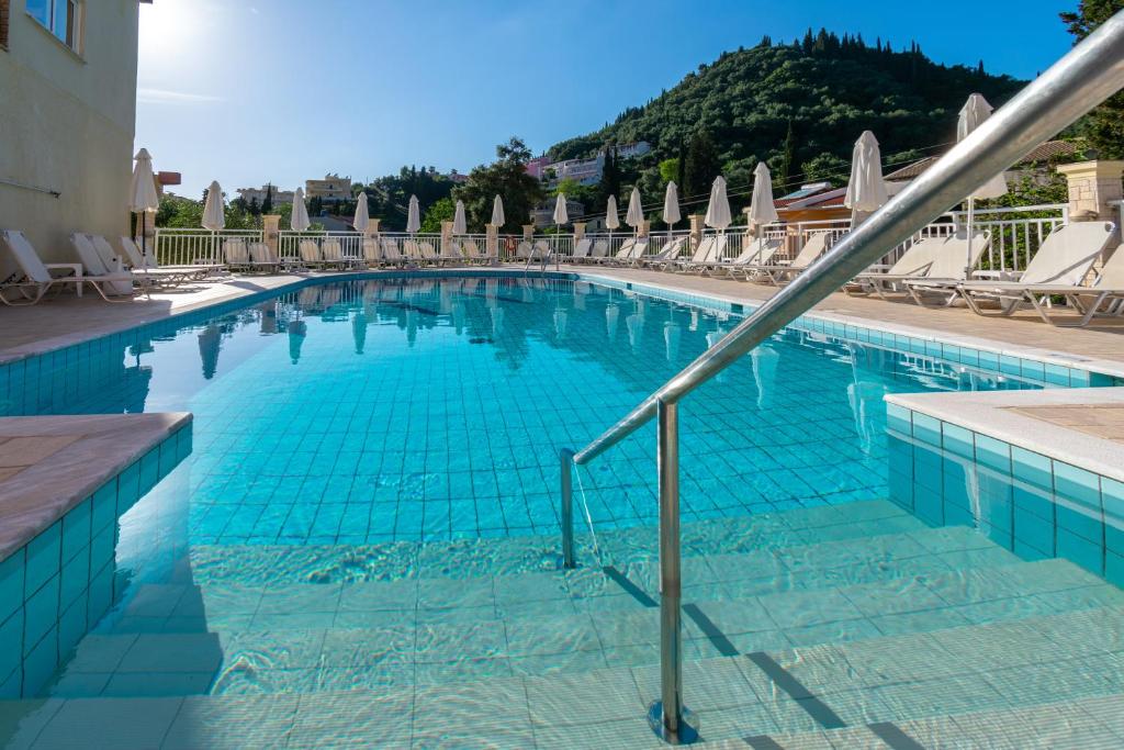 a large blue swimming pool with chairs and umbrellas at Angelica Hotel in Agios Gordios
