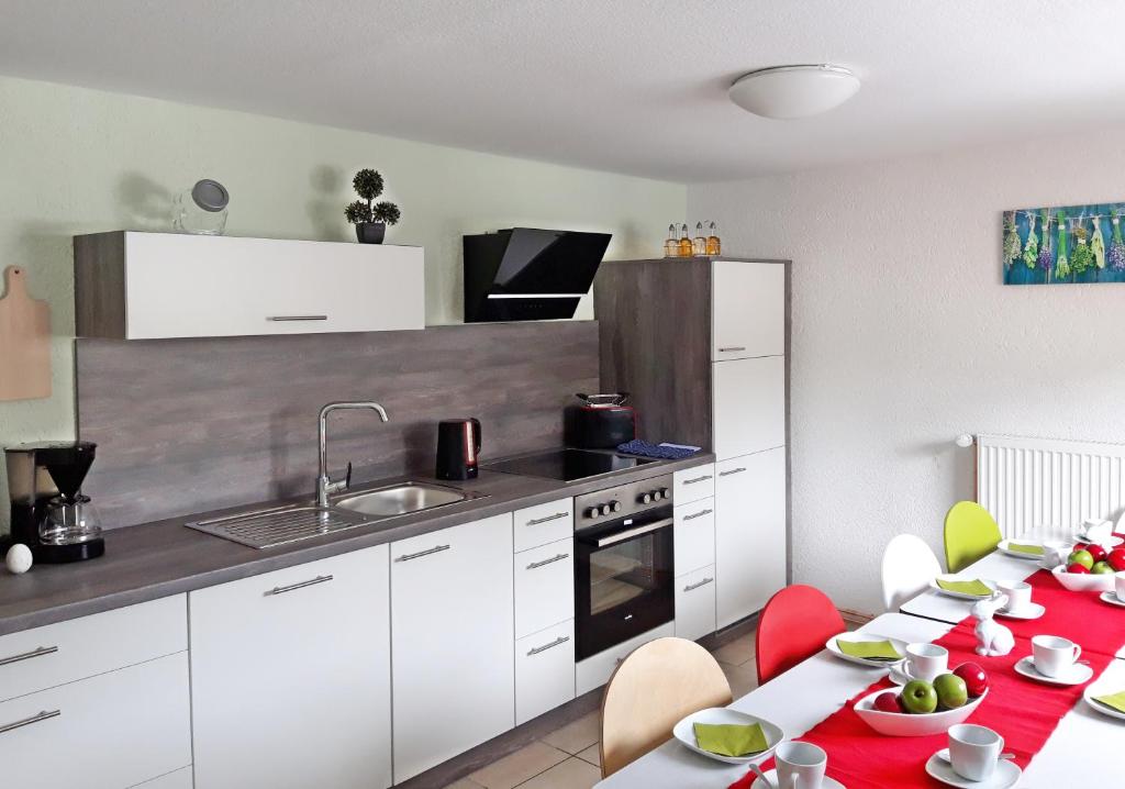 uma cozinha com armários brancos e cadeiras e mesas vermelhas em Haus des Handwerkers em Koblenz