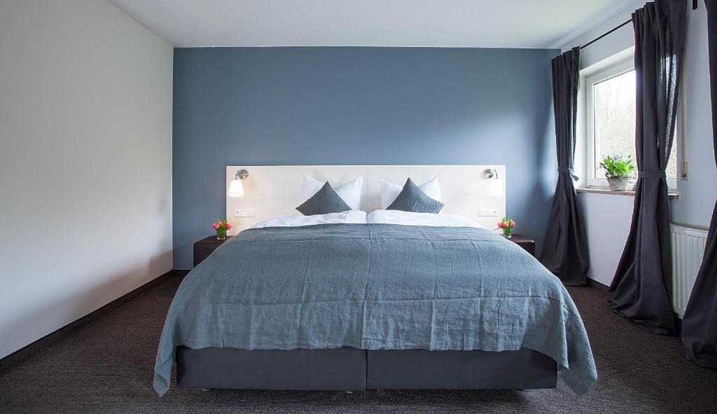 a blue bedroom with a bed with a blue wall at Alpenglühen Smart Hotel in Olching