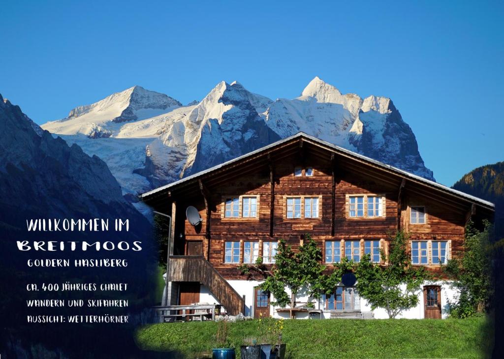 a large wooden building with mountains in the background at Breitmoos in Hasliberg