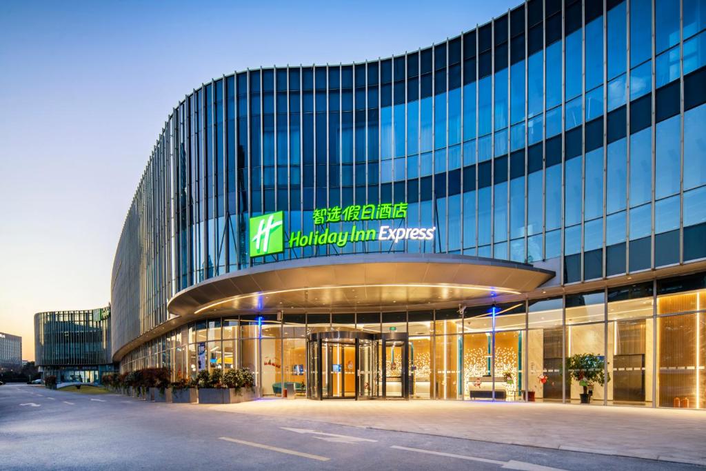 a large glass building with a sign on it at Holiday Inn Express Shanghai Pudong Zhangjiang, an IHG Hotel in Shanghai