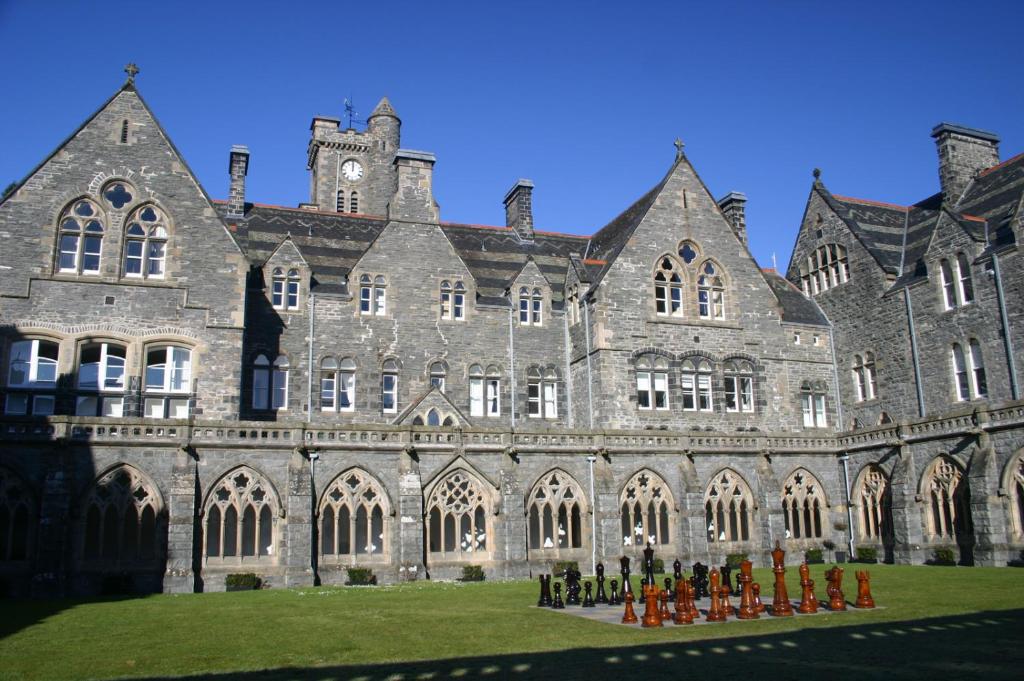 um grande edifício com pessoas de pé na frente dele em The Ness Apartment Highland Club Scotland em Fort Augustus