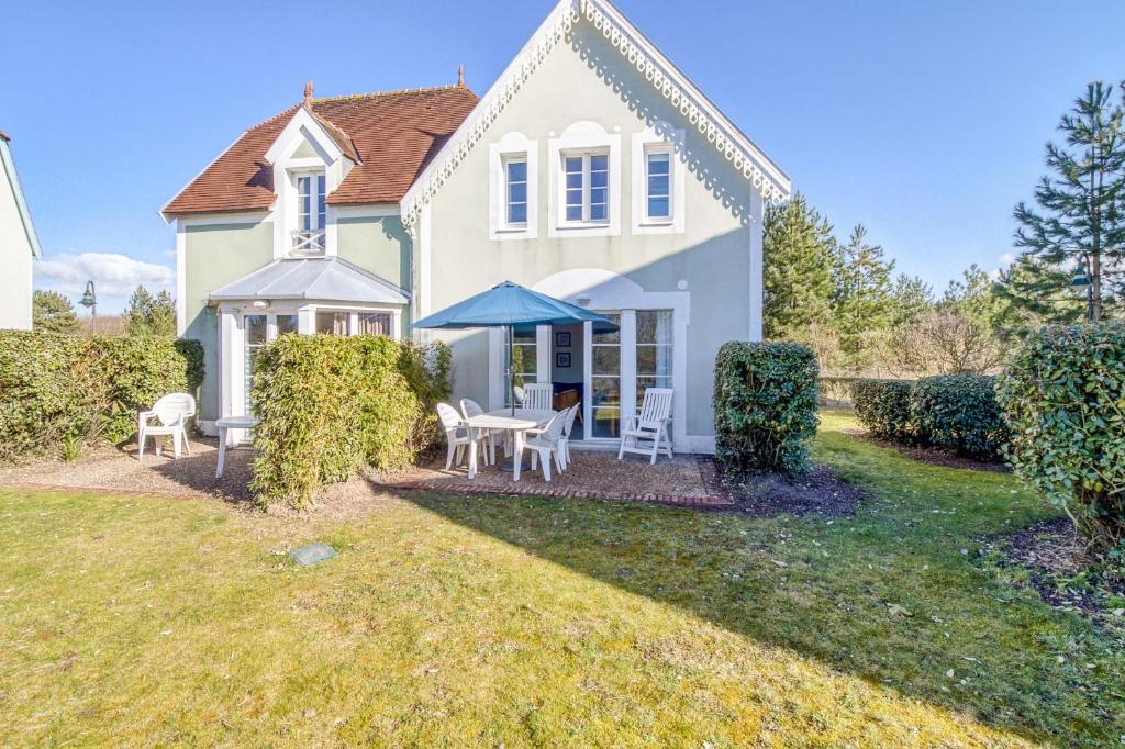a white house with a table and chairs at Belle Dune in Fort-Mahon-Plage