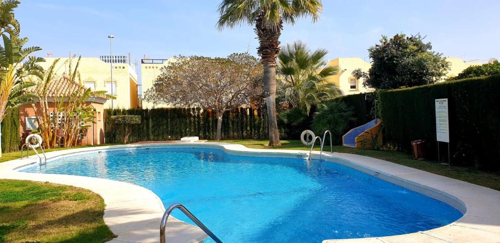a swimming pool in a yard with a palm tree at Vera Sol y Mar - Naturist Zone in Playas de Vera