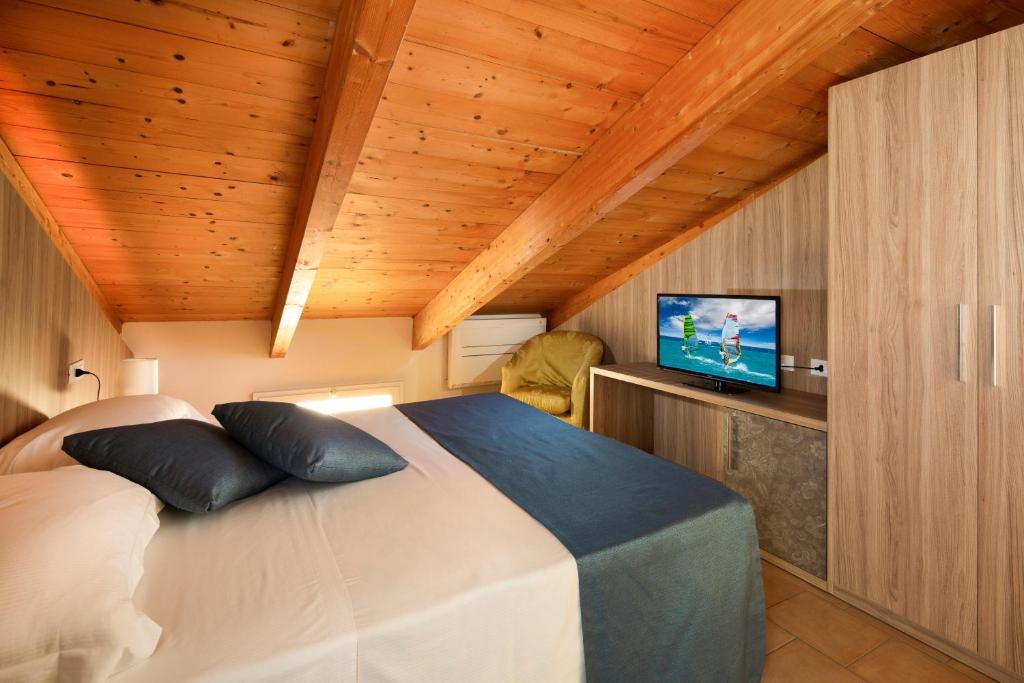 - une chambre avec un lit et une télévision au plafond en bois dans l'établissement Mansarda Cannes, à Riccione