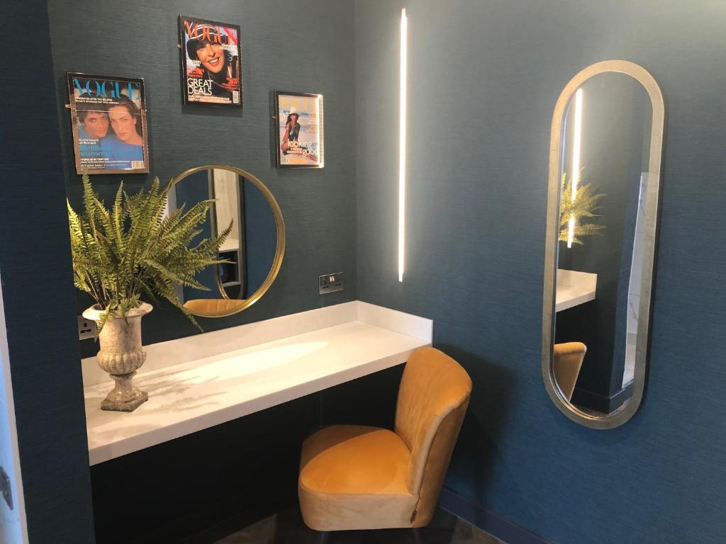 a bathroom with a sink and two mirrors and a chair at Waterfront Southport Hotel in Southport