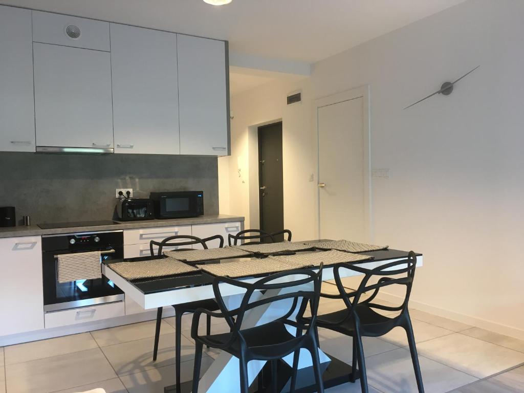 cocina con armarios blancos, mesa y sillas en Apartament Fibra Grande en Rybnik