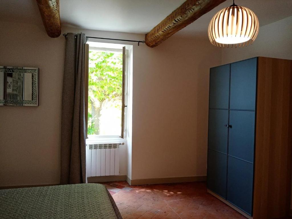 a bedroom with a blue cabinet and a window at LE MAS DES FLANERAIES in Althen-des-Paluds