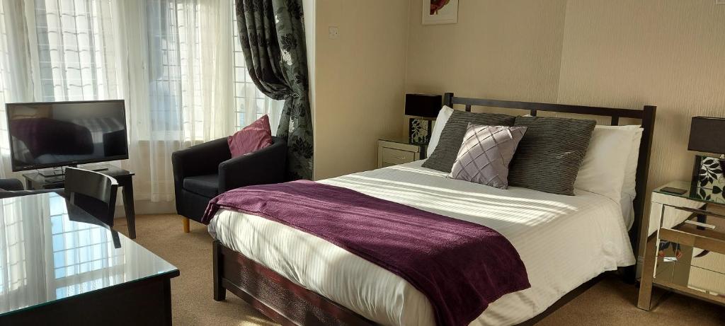 a bedroom with a bed and a couch and a television at Cranmore Bed & Breakfast in Torquay