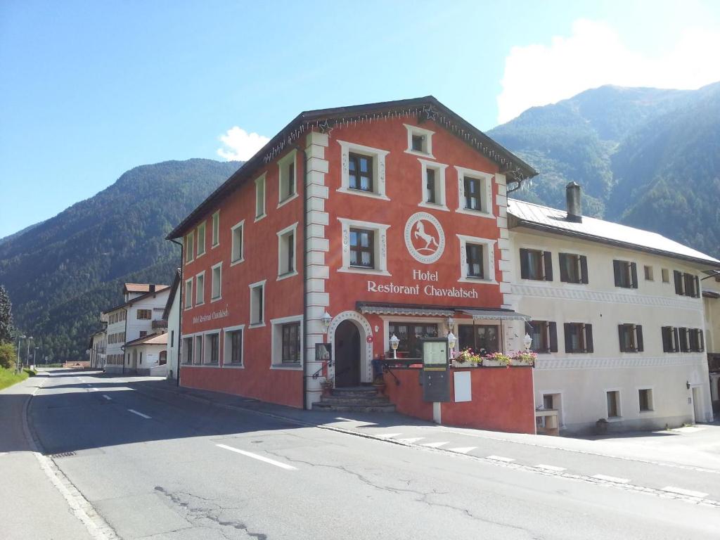 un bâtiment rouge et blanc sur le côté d'une rue dans l'établissement Hotel Chavalatsch, à Müstair