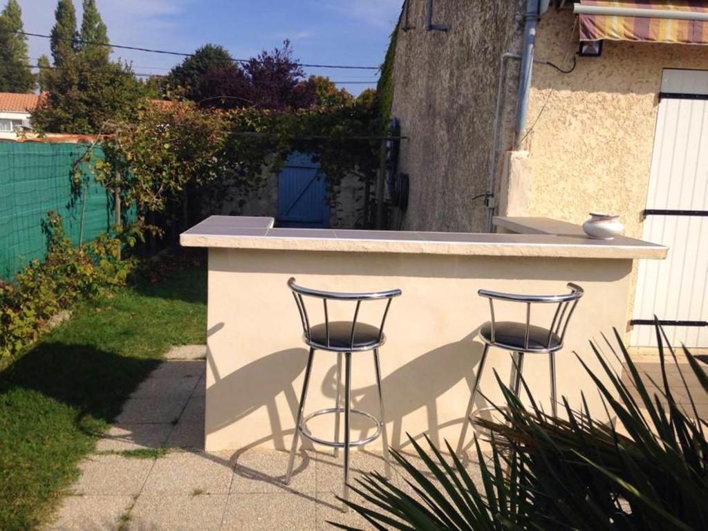 a counter with two bar stools in a backyard at Villa de 4 chambres avec piscine privee jardin clos et wifi a Aytre a 5 km de la plage in Aytré