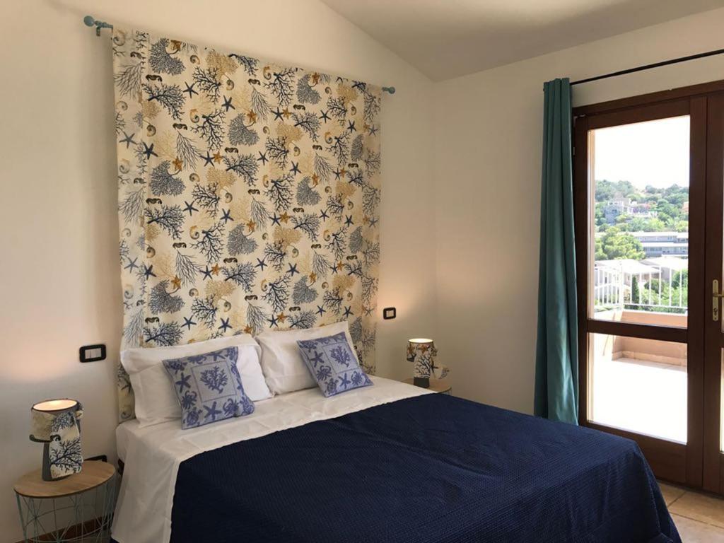 a bedroom with a blue bed and a window at Sa Tirìa in Chia