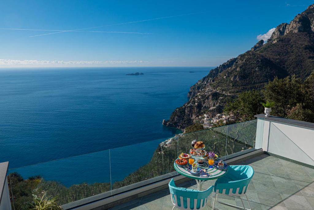 uma mesa e cadeiras numa varanda com vista para o oceano em Petrea Lifestyle Suites em Positano