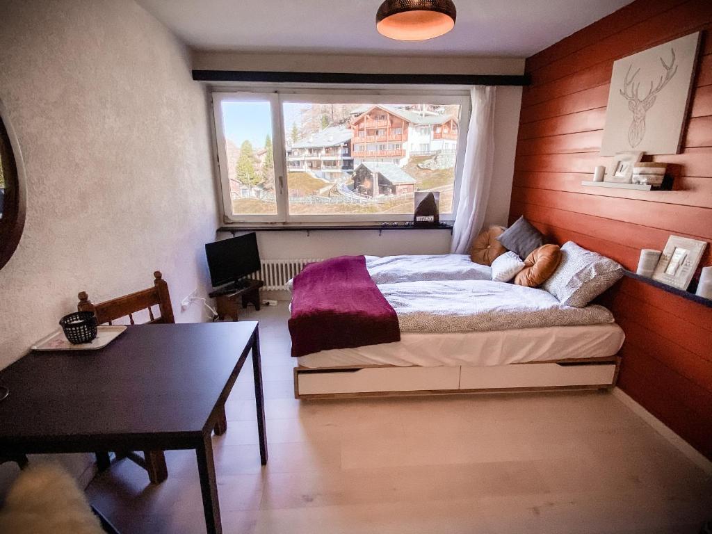 um quarto com uma cama, uma mesa e uma janela em Studio MIA - Cosy & Comfortable - Glacier Paradise em Zermatt