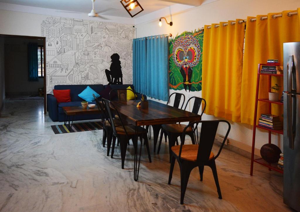 a dining room with a table and chairs and a couch at The Hood Hostel in Bangalore