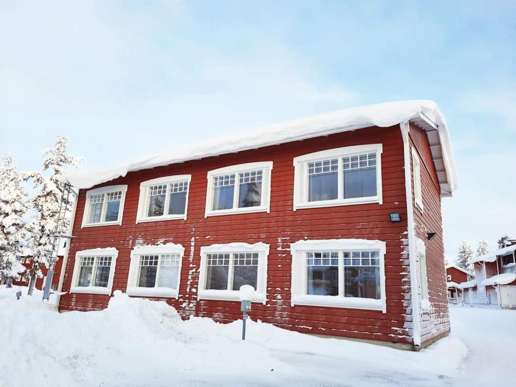 une maison en briques rouges avec de la neige dans l'établissement Lapin Kutsu Luulampi Apartments, à Saariselka
