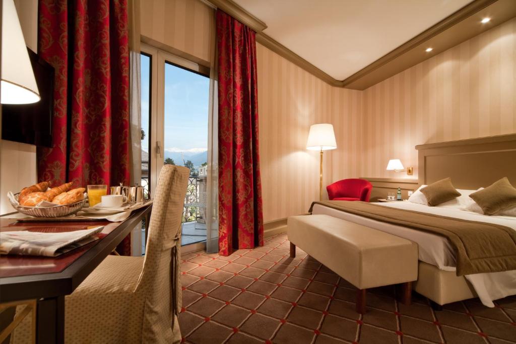 una camera d'albergo con letto, scrivania e finestra di Hotel De La Paix a Lugano