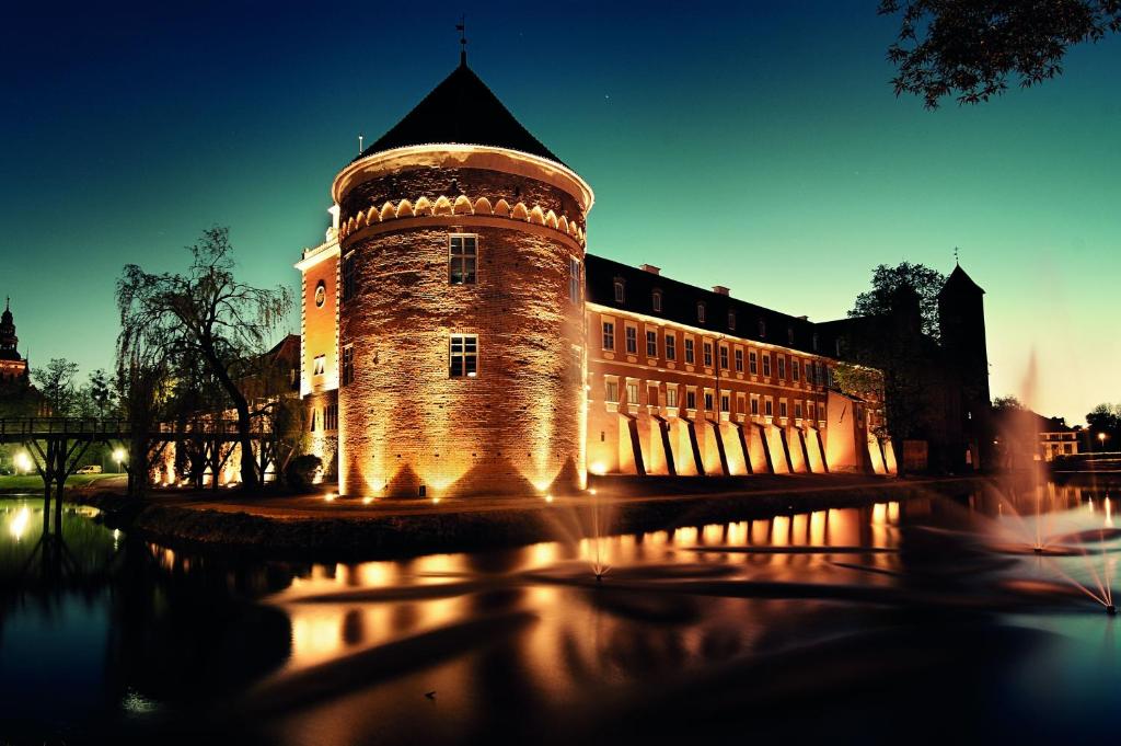 um edifício com uma torre de relógio em frente a um edifício em Hotel Krasicki em Lidzbark Warmiński