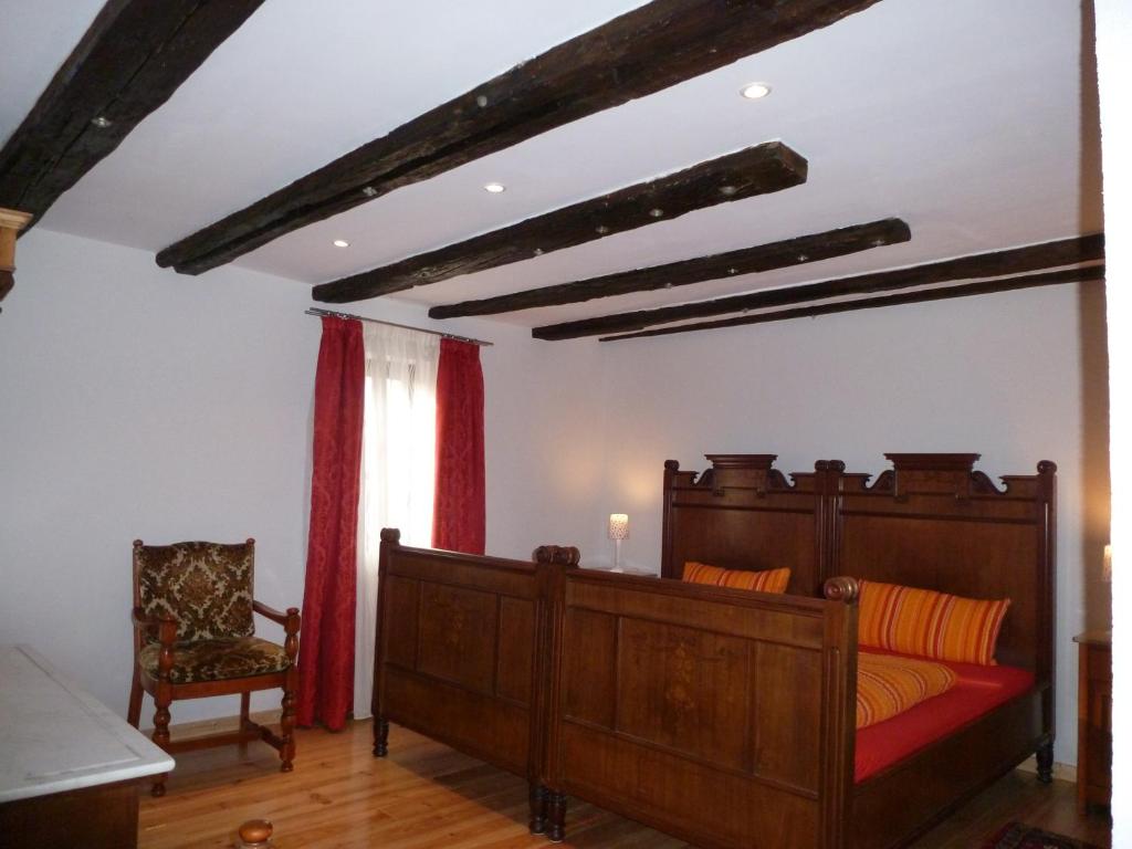ein Schlafzimmer mit einem Bett und einem Stuhl in der Unterkunft Pfälzer Landhotel Heinrich in Bad Dürkheim