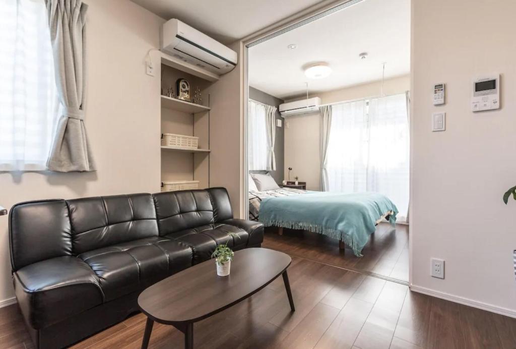 ein Wohnzimmer mit einem Ledersofa und einem Bett in der Unterkunft T-BASE - Vacation STAY 21952v in Tokio