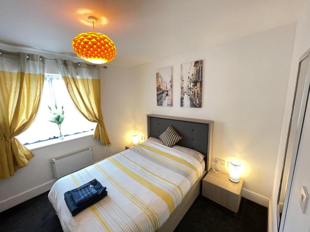 a bedroom with a bed and two lamps and a window at Grand Central Apartments in Derby