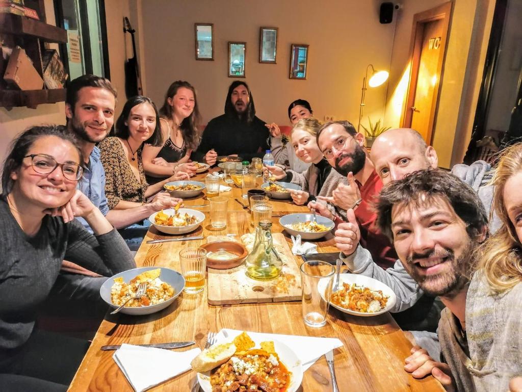 Eine Gruppe von Menschen, die an einem Tisch sitzen und Essen essen. in der Unterkunft El Granado Hostel in Granada