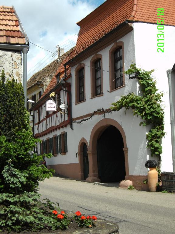 a white building with a door and a street at Pfälzer Landhotel Heinrich in Bad Dürkheim