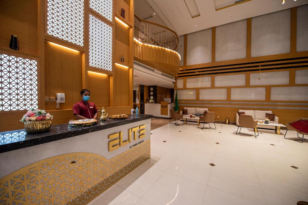 a person standing at a counter in a hotel lobby at Elite Najran in Najran
