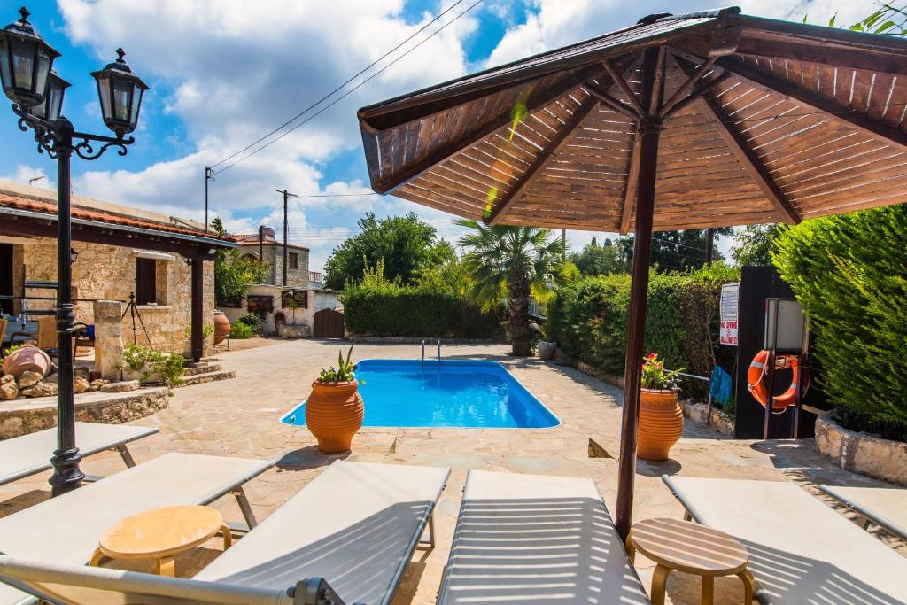 een patio met een parasol en een zwembad bij Karydhia Cottage in Pano Arodes