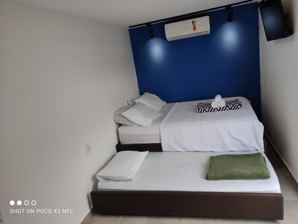 2 łóżka w pokoju z niebieską ścianą w obiekcie Flat Container Pontal do Atalaia w mieście Arraial do Cabo