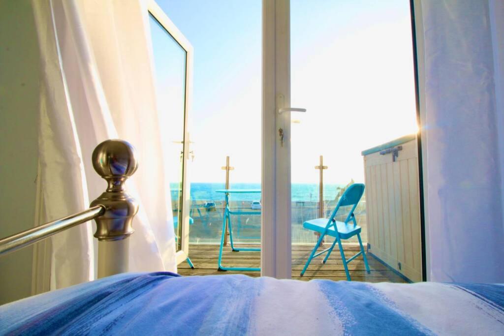 Schlafzimmer mit einem Bett und Blick auf einen Balkon in der Unterkunft Serenity "your calm seafront retreat" By Air Premier in Seaford