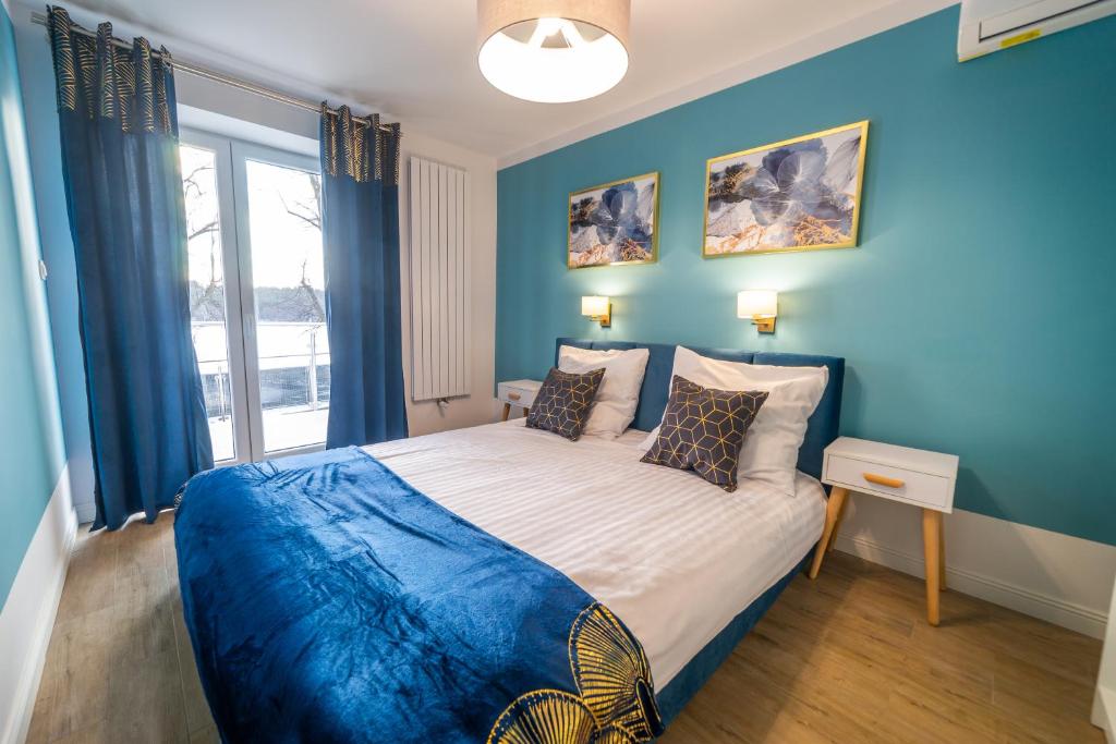 ein Schlafzimmer mit blauen Wänden und einem großen Bett in der Unterkunft Lawendowe wzgórze Apartamenty in Mikołajki
