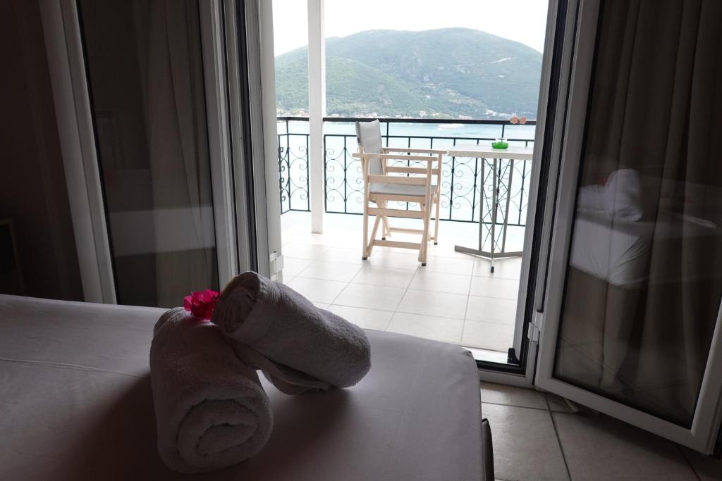 a hotel room with a towel on a bed and a balcony at Sea Sound in Vasiliki