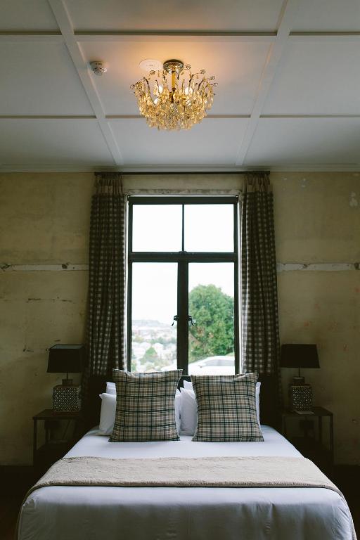 a bedroom with a bed with a window and a chandelier at The Convent Hotel in Auckland